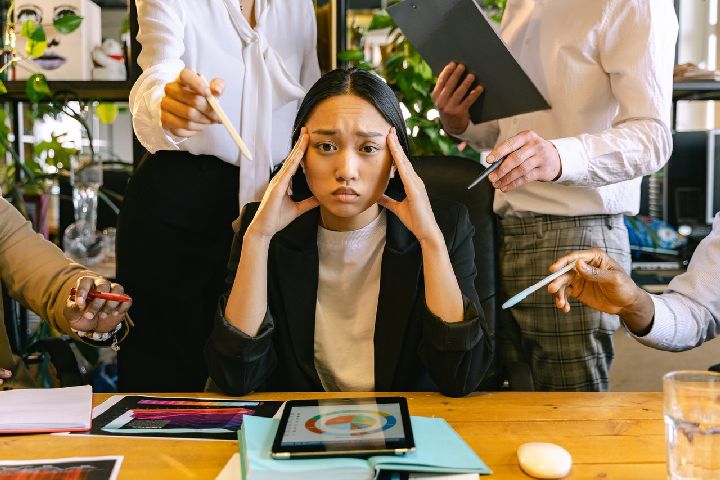 young business woman looking stressed with people standing around her